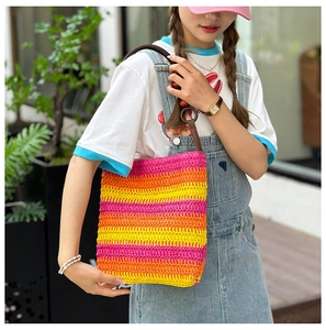 Close-up of rainbow striped woven bag with brown strap on a model shoulder