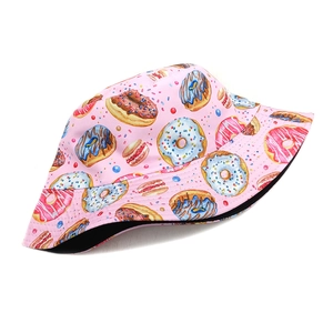 Detailed view of pink reversible bucket hat with colorful doughnut and macaron prints
