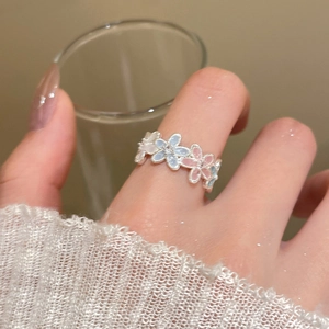 Detail of colorful enamel flower ring featuring pink and blue blossoms on finger