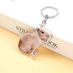 Detailed view of capybara acrylic keychain with metal ring on a book surface
