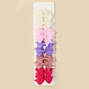 Detailed close-up of 5 colorful ribbed ribbon bow clips on a display card for girls