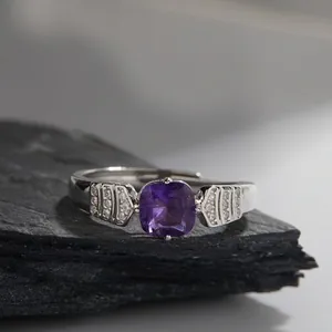 Macro shot of a square purple amethyst ring with micro-pave zircons on a dark stone base