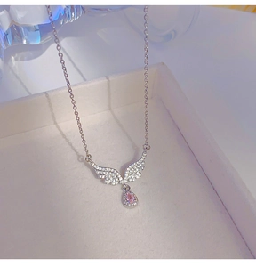 Macro view of silver angel wing necklace with a sparkling pink teardrop zircon stone
