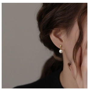 Macro side view of elegant s925 silver pearl earring worn on model for detail