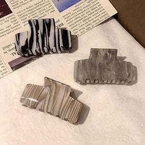 Three acetate hair claws in ink-pattern marble and zebra print on vintage newspaper