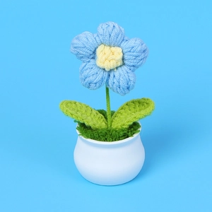 Makroaufnahme einer gehäkelten Blume im weißen Keramiktopf auf blauem Hintergrund
