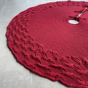 Detail of red cable-knit Christmas tree skirt showing intricate knit patterns and tie closure