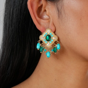 Macro detail of bohemian vintage earring featuring emerald green stone and blue water drop beads