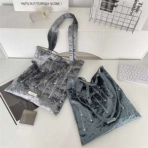 Top view of two velvet tote bags with pearl bead tassels and modern lifestyle props