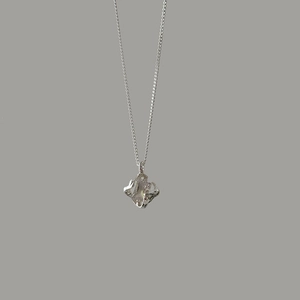 Macro detail of 18k silver plated necklace featuring irregular liquid metal pendant