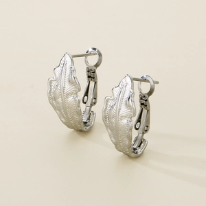 Detailed view of silver feather earrings with intricate carved leaf texture and clasp
