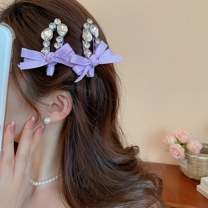 Détail d'une barrette à nœud violet avec cristaux brillants portée sur le côté