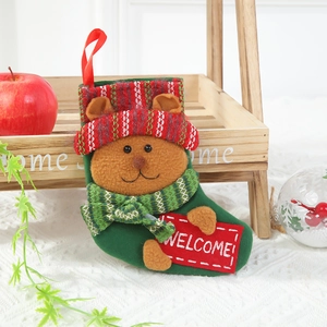 Detail of green plush Christmas stocking featuring a brown bear holding a Welcome sign