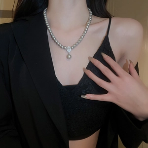 Close-up of grey pearl necklace with a sparkling waterdrop pendant on a black outfit