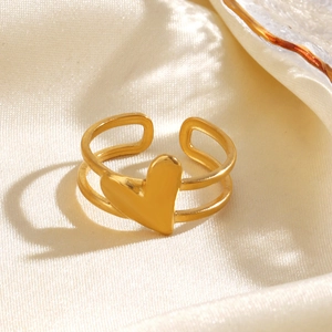 Minimalist gold heart-shaped open ring placed on elegant beige silk fabric background