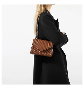 Detail view of caramel brown quilted shoulder bag with V-pattern stitching and chain strap