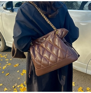 Close-up of dark brown quilted chain bucket bag with FASHION & BAGS lettering
