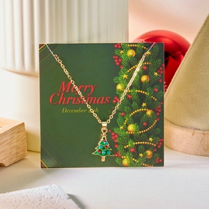 Detail of Christmas tree pendant with green enamel and rhinestones on card packaging
