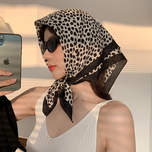 Detailed view of black and white leopard print silk scarf with artistic shadow lighting