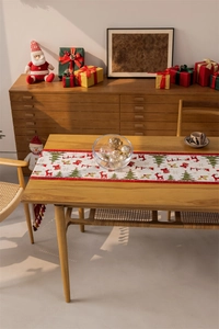 Detailed close-up of beige Christmas table runner with festive reindeer and tree patterns