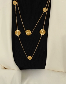 Detail of layered gold titanium necklace with sunburst texture and crystal charms
