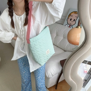 Close-up of heart-shaped quilted pattern on mint green nylon shoulder bag with pink strap