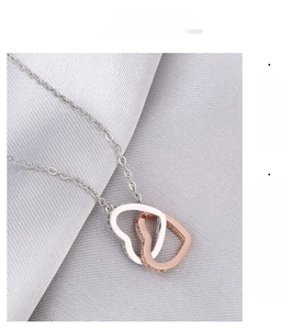 Close-up of interlocking heart necklace in silver and rose gold on silk fabric