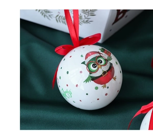 Close-up of a white Christmas ball with owl illustration and Merry Christmas ribbon detail
