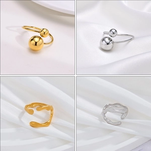 Irregular wave and double ball open rings in gold and silver finish on white fabric