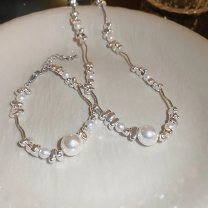 Elegant pearl and irregular silver bead necklace and bracelet set on ceramic plate