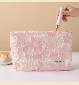 Close-up of pink embroidered linen makeup bag with 3D floral jacquard and zip closure