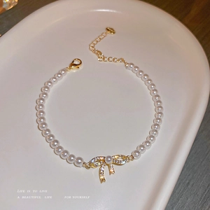 Baroque bow pearl bracelet with gold plating and crystals on a ceramic tray