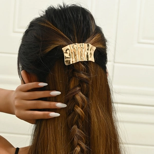 Golden wavy irregular metal hair clip worn on braided hair with high gloss finish