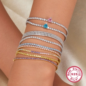Primo piano di bracciali tennis in argento 925 con zirconi colorati sovrapposti sul polso