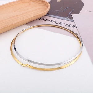 Detailed close-up of minimalist flat chokers in gold and silver finish on a wooden tray