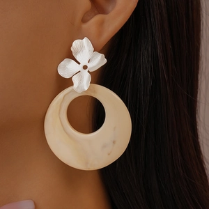 Detail of silver brushed flower stud earrings with beige resin circle on model