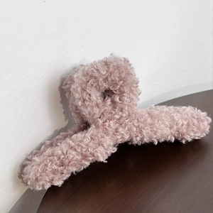 Close-up of pink plush hair claw clip made of teddy fleece on a dark wooden surface