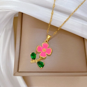 Détail du collier doré avec fleurs en émail rose et feuilles en pierres précieuses vertes