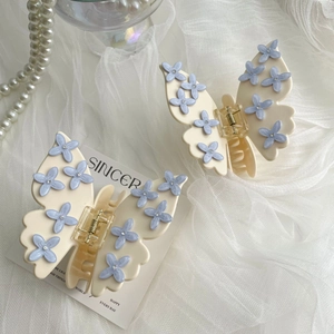 Exquisite butterfly hair claw with blue floral patterns on creamy white resin wings