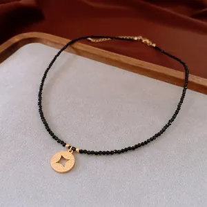 Collier en perles noires avec pendentif étoile dorée sur un plateau en velours chic