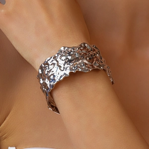 Detailed view of silver metallic wide cuff bracelet with hammered liquid texture on wrist