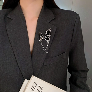 Détail d'une broche papillon noire à pompon sur le revers d'un tailleur gris foncé