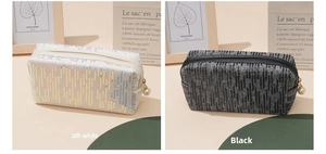 Close-up of off-white and black sequin makeup bags featuring elegant pearl zipper pulls