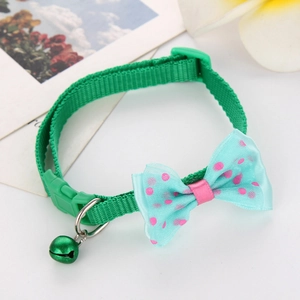 Detail of green nylon pet collar with polka dot bow and small bell on white background
