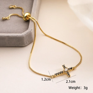 Detail view of 18K gold plated cross bracelet with black and white zircon stones