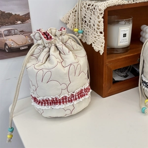 Detailed close-up of quilted drawstring pouch with red rabbit embroidery and lace trim