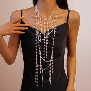Detail of layered faux pearl body chain necklace with golden accents on black dress
