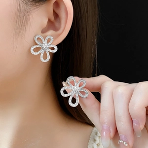 Gros plan de boucles d'oreilles fleurs évidées en argent avec petits zircons brillants