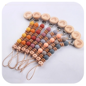 Detail of seven colorful silicone and beech wood pacifier clips arranged in a fan shape