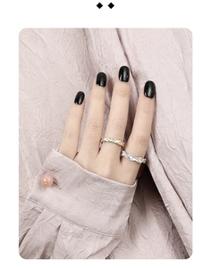 Detail of minimalist wavy hammered silver rings on hand with lavender background